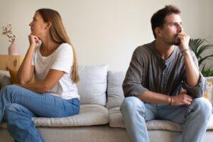 Young couple ignoring each other sitting on the couch. Couple fighting at home. Relationship difficulties concept.